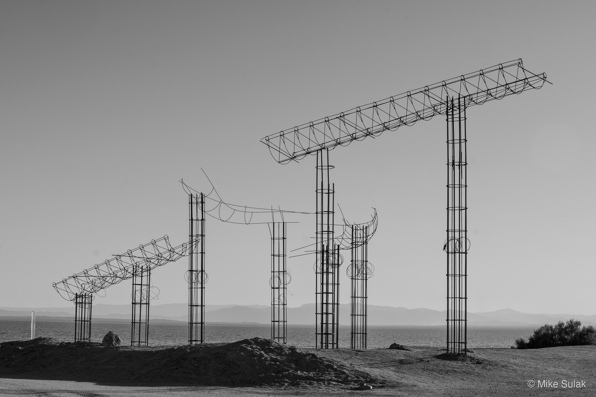 Tall wire sculptures in a flat desert landscape